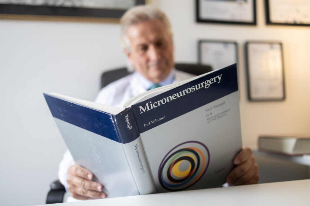 Foto del neurochirurgo Alessandro Della Puppa che legge un libro di Neurochirurgia